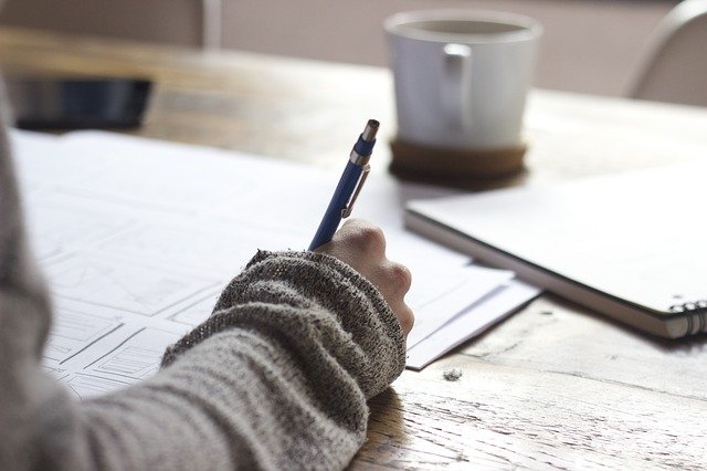 Femme qui travaille et note ses idées sur des carnets