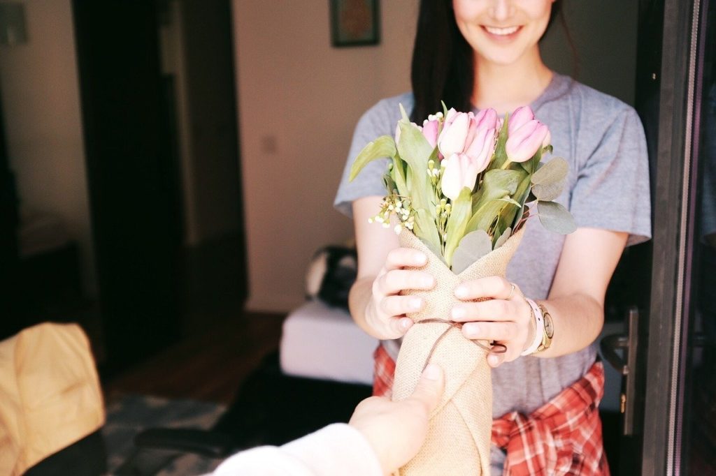 Femme souriante qui reçoit un bouquet de fleurs