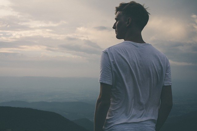 Homme en t-shirt blanc bras nus qui regarde l'horizon