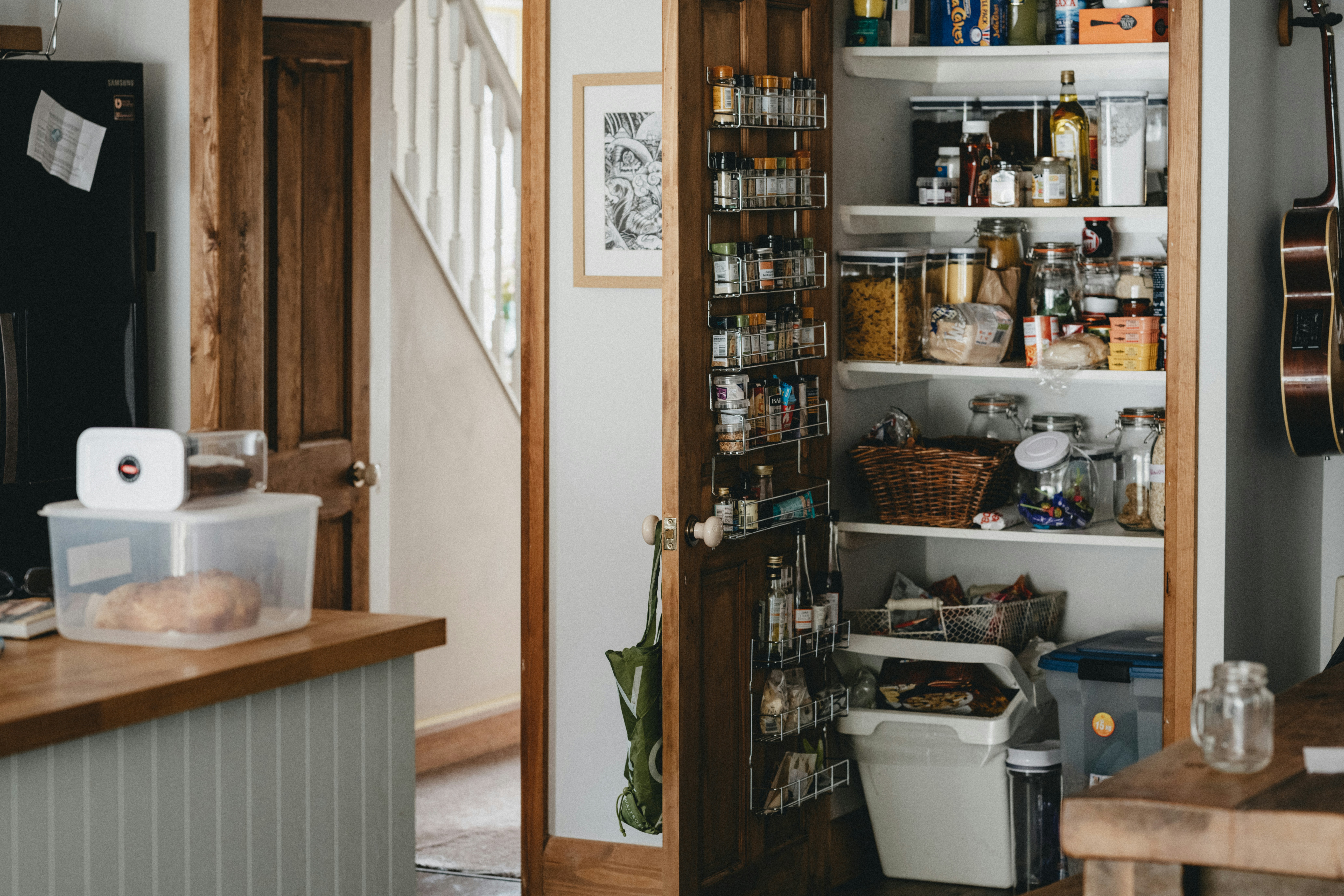 Photo d'un placard de cuisine très rempli. On y voit des aliments sec, des pots d'épices et des bouteilles de condiments.