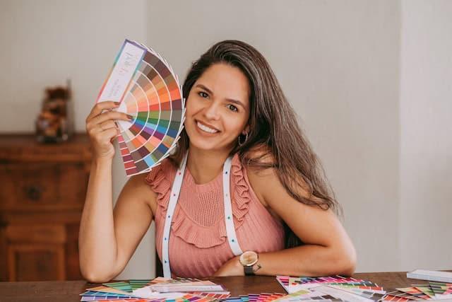 Femme avec un mettre ruban autour du cou et qui tient une palette de couleurs à côté de son visage